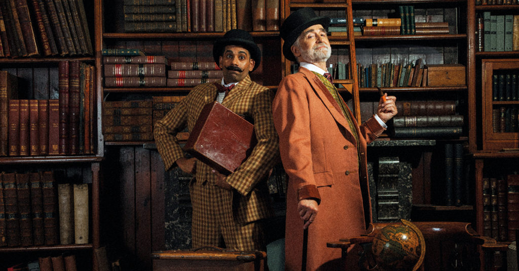 Two men (Darren Kuppan and Robert Pickavance) in Victorian costume, one with a moustache, bowler hat and suitcase and one with a top hat, beard and pipe.